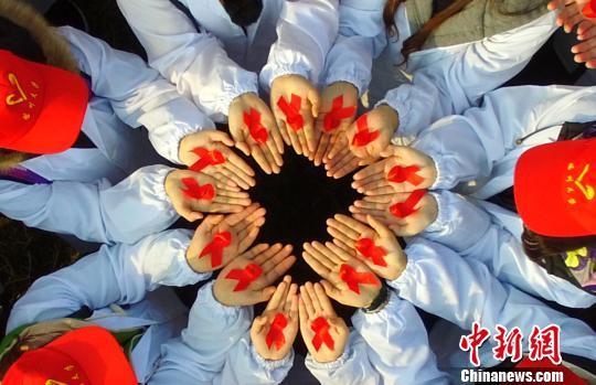 百名大学生摆巨型“红丝带”呼吁消除艾滋病歧视(图4) 图为大学生展示防艾标志红丝带。 孟德龙 摄
