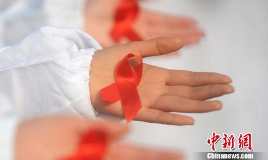 百名大学生摆巨型“红丝带”呼吁消除艾滋病歧视(图5) 图为大学生展示防艾标志红丝带。 孟德龙 摄