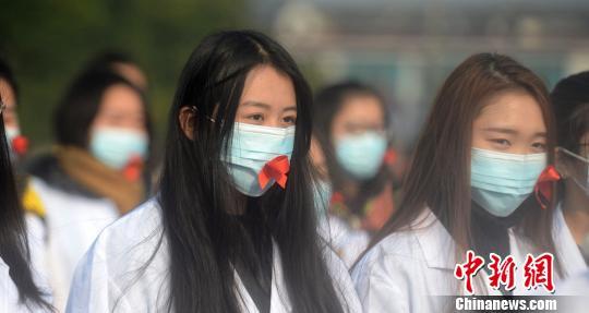 百名大学生摆巨型“红丝带”呼吁消除艾滋病歧视(图6) 图为大学生们戴粘有红丝带的口罩。 孟德龙 摄